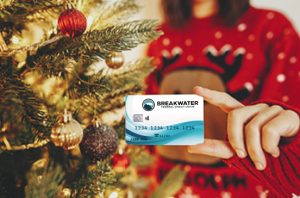 Woman next to a Christmas tree, holding a credit card